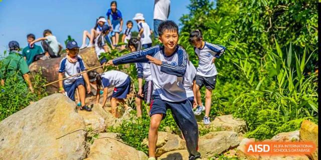 A student from BASIS International & Bilingual Schools Chengdu participating in a rock climbing or outdoor obstacle course.