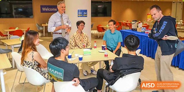 Students and teachers from BASIS International & Bilingual Schools Chengdu sitting at a table in a group, talking.