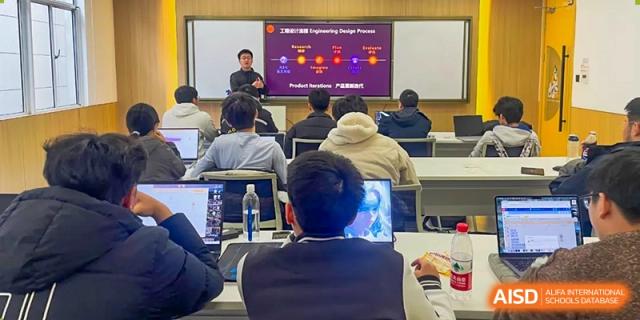 AcaBridge Academy students attending a presentation or lecture in a classroom, viewing slides projected onto a screen at the front of the room.