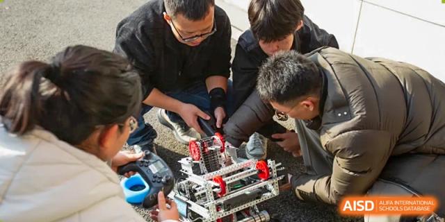 A small group of AcaBridge Academy students working together on an engineering or robotics project, examining and assembling metal and electronic components.