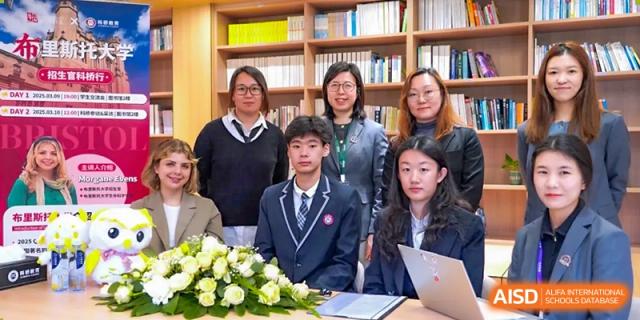A group of AcaBridge Academy students and teachers posing for a formal photo indoors, seated at a table with flowers.