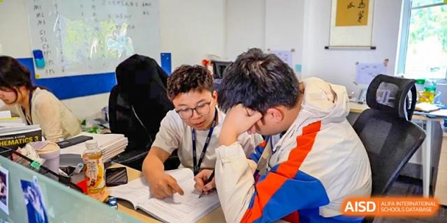 Two focused AcaBridge Academy students collaborating intensely, looking down at papers and working on a project together.