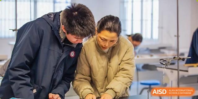 Two AcaBridge Academy students leaning over a table, working together and focusing intently on a project or document.
