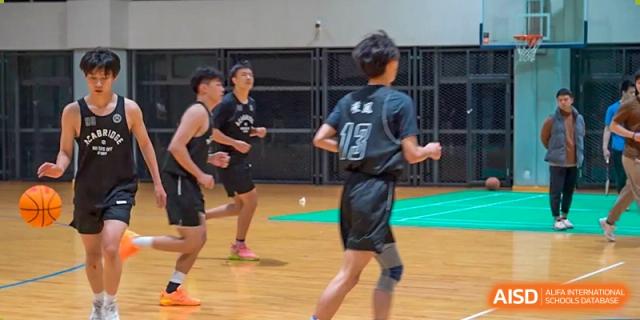 AcaBridge Academy students playing basketball, running on a wooden court. One student with the number '13' on his jersey is in the foreground.