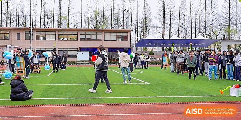 AcaBridge Academy students walking on the running track and field during an outdoor school event on a grassy area near a building.