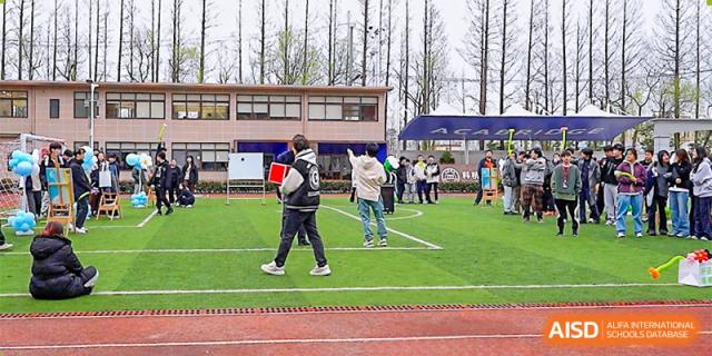AcaBridge Academy students walking on the running track and field during an outdoor school event on a grassy area near a building.