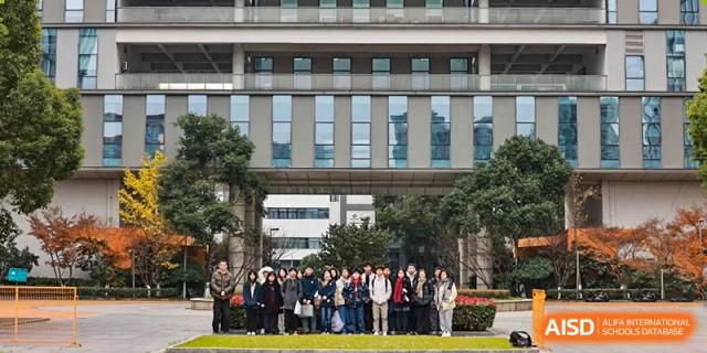 A large group of AcaBridge Academy students posing together for a photo in front of a modern school building and plaza.