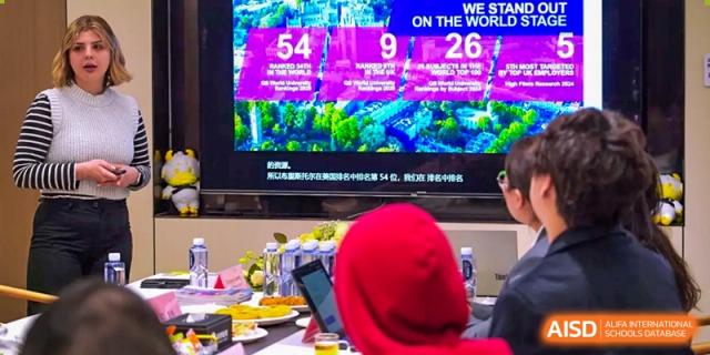 An AcaBridge Academy student watching a vibrant video or news on a large screen while working on a laptop.