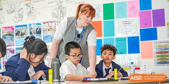 A teacher at Merchiston International School Shenzhen provides personalized instruction to a small group of young students during an activity.