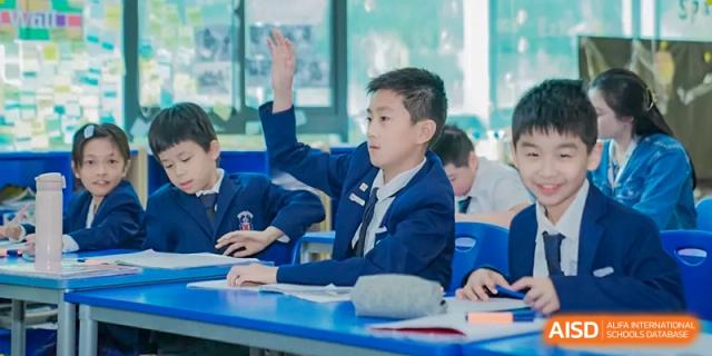 A highly engaged Merchiston International School Shenzhen student enthusiastically raises his hand to answer a question in class.