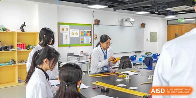 A teacher or instructor in a lab coat guiding Merchiston International School Shenzhen students through an experiment or practical activity in a science room.