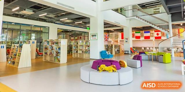 A wide view of the modern, brightly lit library or learning hub at Merchiston International School Shenzhen, featuring study areas and book shelves.