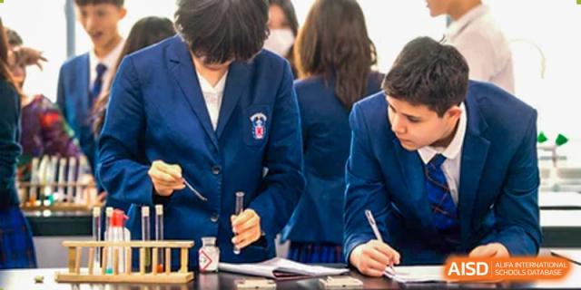 Merchiston International School Shenzhen students in their uniforms carefully conducting a science experiment using test tubes and liquids in a laboratory setting.
