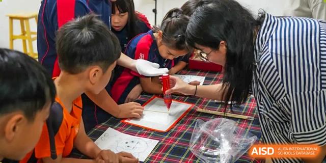 Merchiston International School Shenzhen students collaborating closely on a hands-on project or experiment on the floor, supervised by an adult.