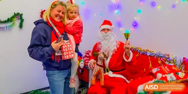 A family with young children posing happily with Santa Claus during a festive Christmas celebration hosted by Merchiston International School Shenzhen.