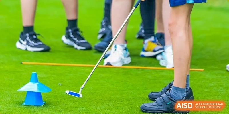 A close-up shot of a student's feet and a golf club on a green turf, representing a PE or sports lesson at Merchiston International School Shenzhen.