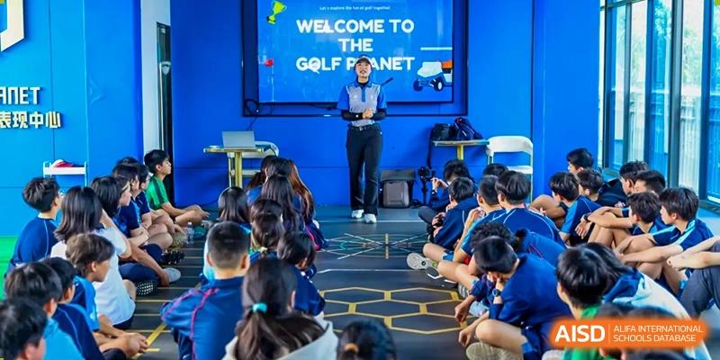 A group of Merchiston International School Shenzhen students sitting and watching an instructor during an indoor golf lesson or sports presentation.