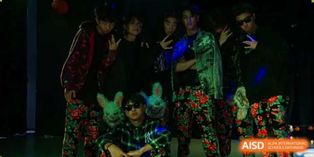 A group of older Merchiston International School Shenzhen students posing together in colorful, themed costumes during a school event.