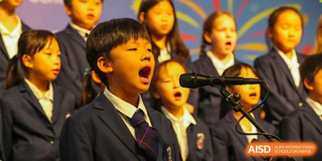 Close-up of Merchiston International School Shenzhen students in uniform singing passionately into microphones during a school performance.