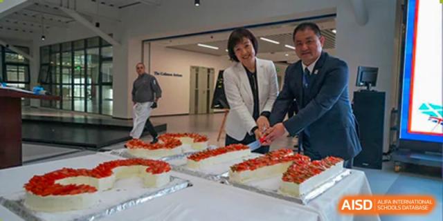 School leaders and staff at Merchiston International School Shenzhen preparing to cut a large cake during a celebration or anniversary event.