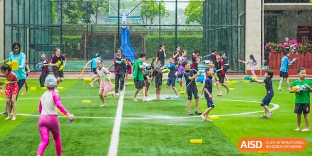 Merchiston International School Shenzhen students and staff participating in fun water games and running activities on the outdoor turf field.