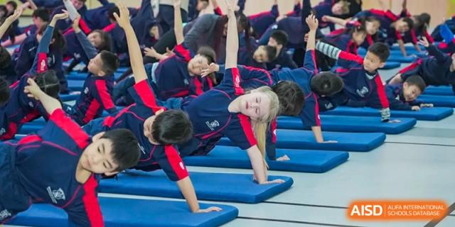 Close-up of Merchiston International School Shenzhen students performing a yoga or stretching pose on mats during a physical education class.