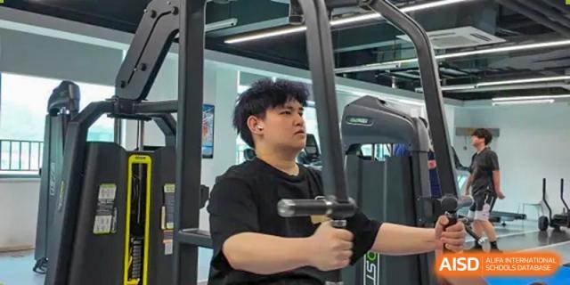 A Merchiston International School Shenzhen student using a weight machine or exercise equipment in the school's modern fitness center or gymnasium.