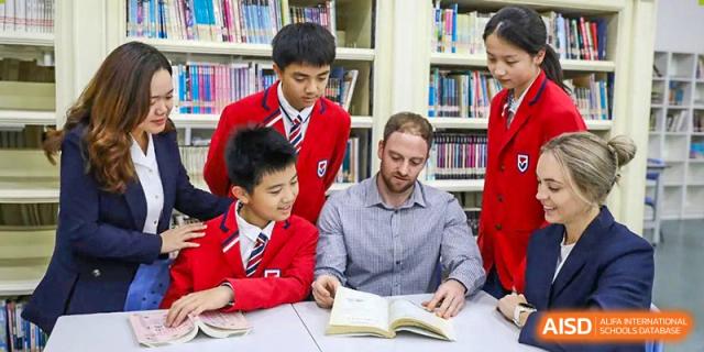 A teacher from Guangdong Country Garden School sits with students in the library, reading a book aloud to them.
