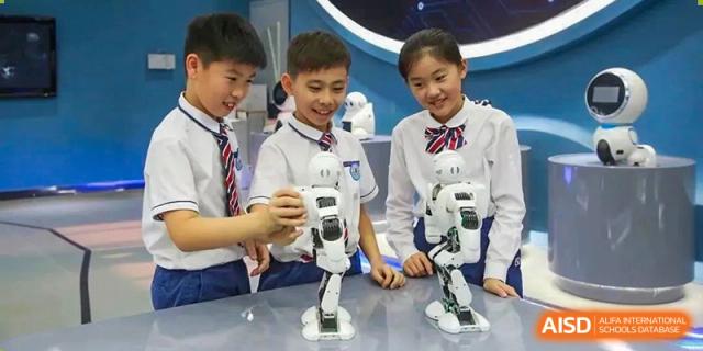 Two students from Guangdong Country Garden School in school uniforms work with a white robot in a classroom.