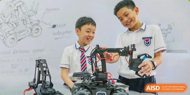Students from Guangdong Country Garden School work with a teacher on a robotics or engineering project in a classroom.