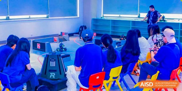 A teacher from Guangdong Country Garden School sits with students, helping them in a classroom setting.