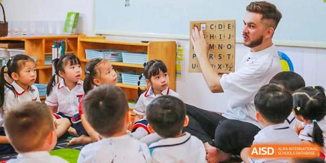 A young female student from Guangdong Country Garden School raises her hand to answer a question in a classroom.
