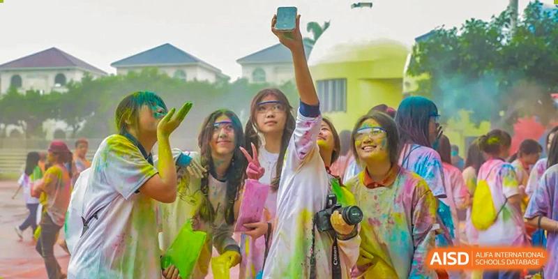 A group of male and female students from Guangdong Country Garden School in casual clothing poses for a photo, cheering with their hands up.