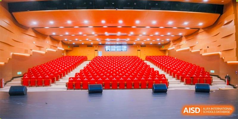 A large, empty auditorium with rows of red seats at Guangdong Country Garden School.
