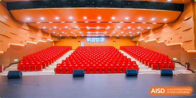 A large, empty auditorium with rows of red seats at Guangdong Country Garden School.