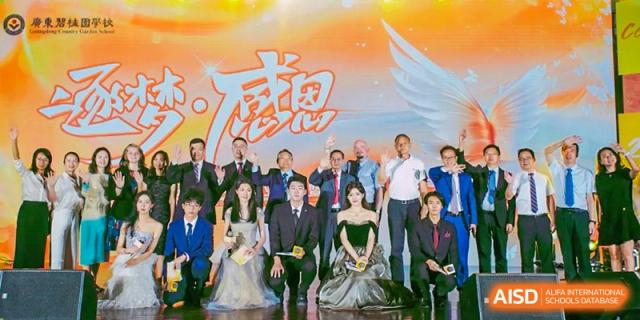 A group of male and female students from Guangdong Country Garden School in formal attire poses for a photo at a gala or event.