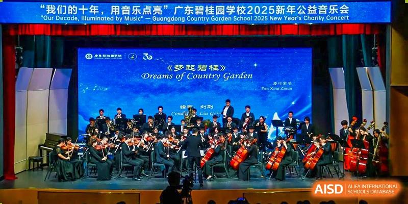 Students from Guangdong Country Garden School perform with an orchestra on stage under a screen displaying the school name and event title.