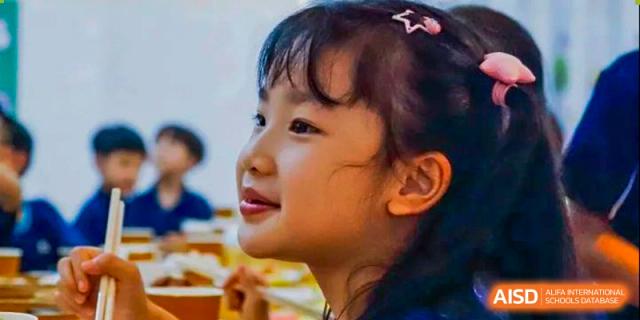 A close-up side profile of a young female student from Guangdong Country Garden School smiling.