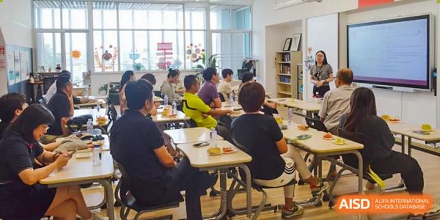 A group of students is seated at desks for a class at Shenyang International School.