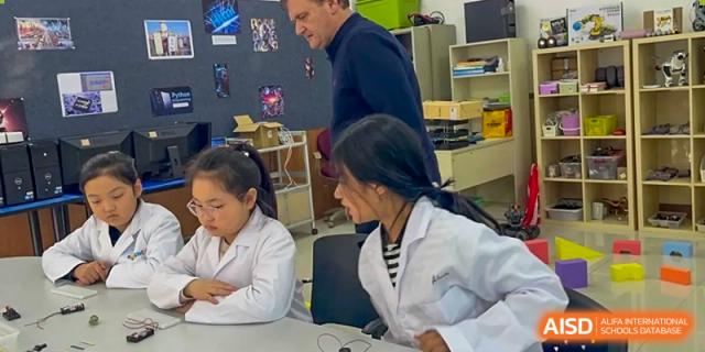 A teacher is observing a student working on a computer at Shenyang International School.