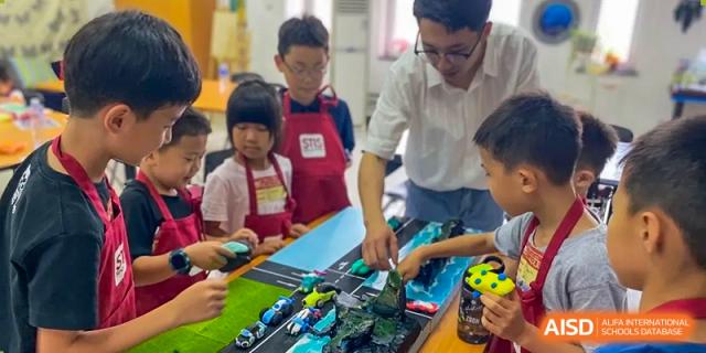 Students and a teacher are working on a diorama at Shenyang International School.
