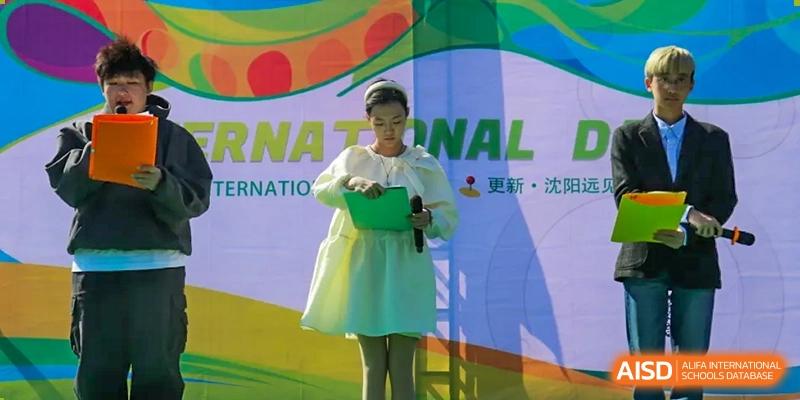 A woman is standing on a stage speaking at an event at Shenyang International School.