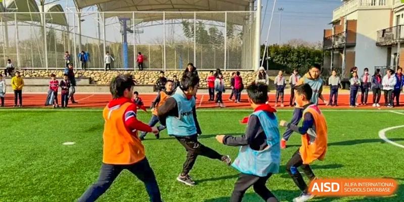 Students are playing a team game on a grassy area at Shenyang International School.