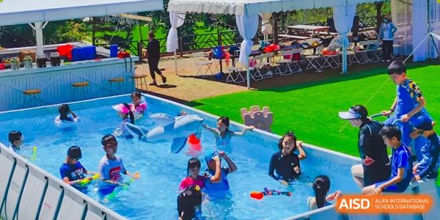 Students are playing in an outdoor swimming pool at Shenyang International School.