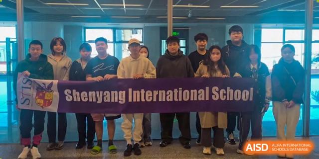 A group of students is holding a banner that says "Shenyang International School."
