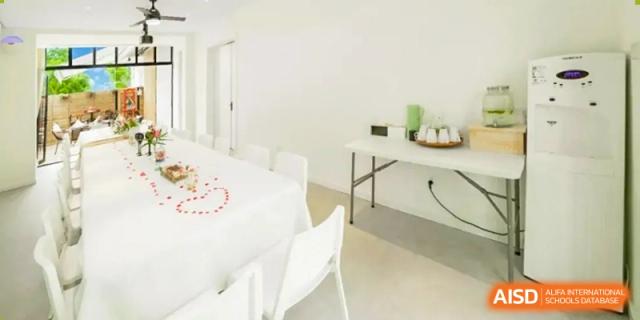 A white room is set up with tables and chairs for a small event at Shenyang International School.