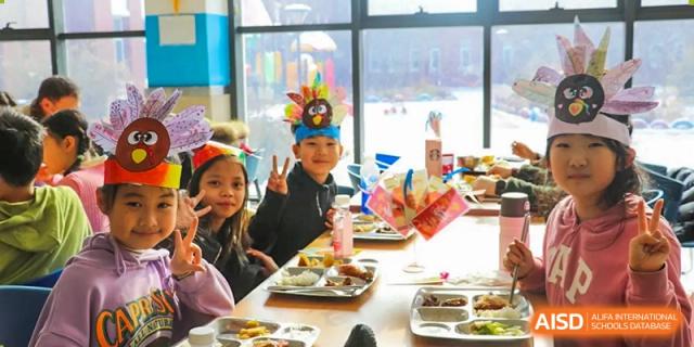 A boy and a girl are seated at a table with plates of food at Shenyang International School.