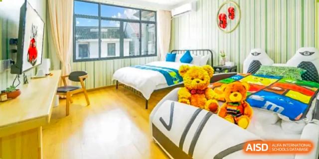 A bed and a large teddy bear are in a bedroom in the dormitory at Shenyang International School.