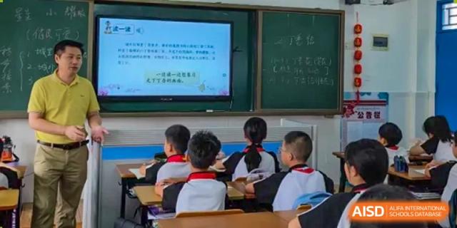 A small group of Shenzhen Yaohua Experimental School students sitting at desks, facing a presentation on a screen in a classroom.