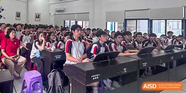 A group of Shenzhen Yaohua Experimental School students seated at desks in a classroom, with one student leaning on a desk with a keyboard.